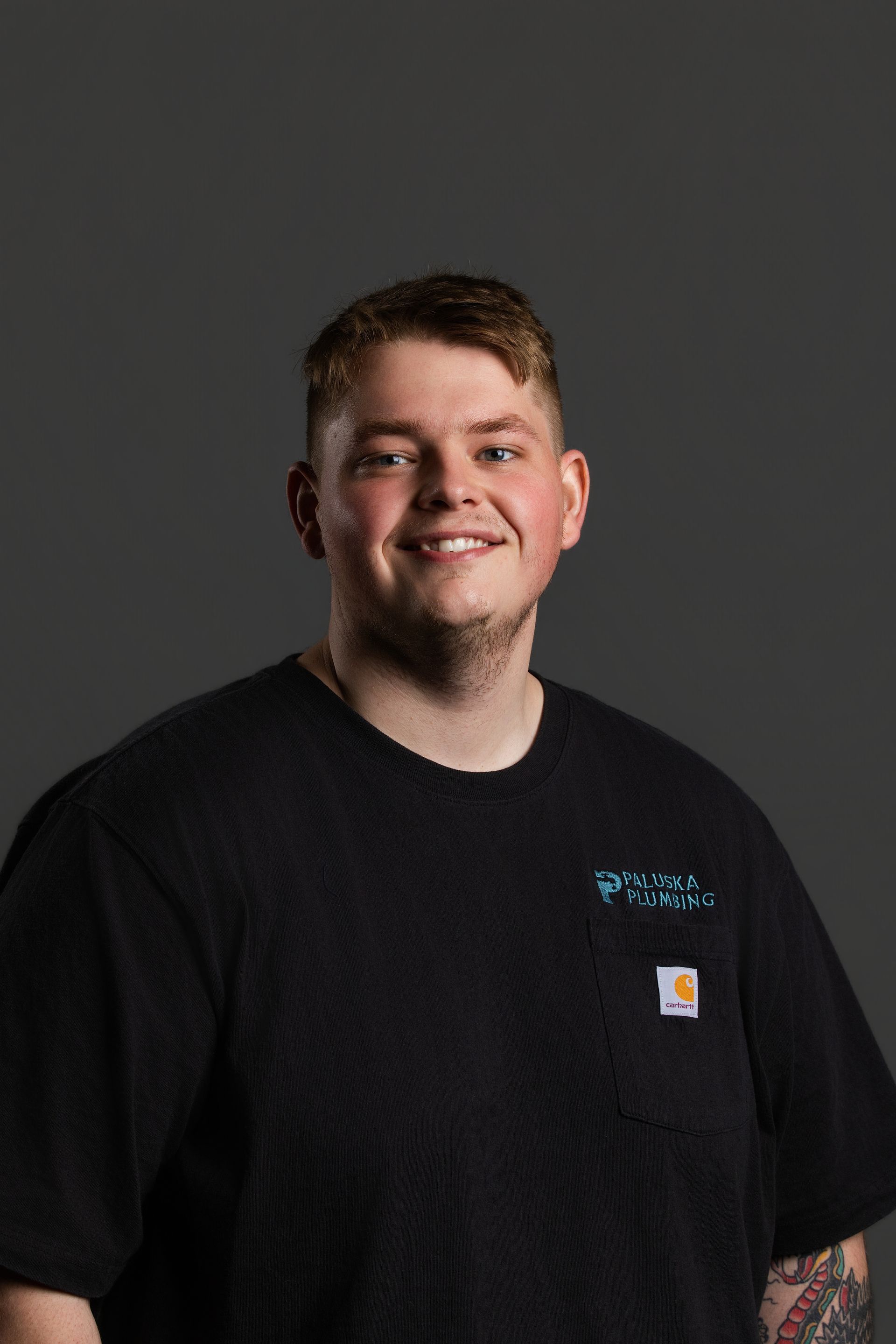 Smiling person in a black T-shirt against a dark gray backdrop.