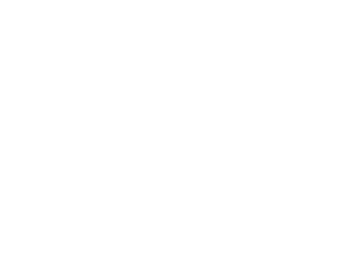 Una persona con una camisa azul está de pie junto a un escritorio con una computadora portátil, señalando un gran monitor que muestra gráficos de datos.