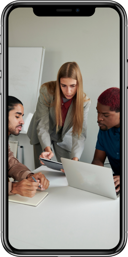 A group of people are sitting around a table looking at a laptop.