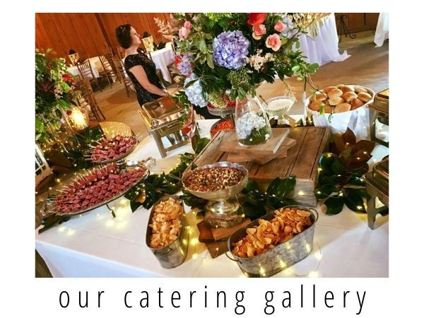 Catering buffet table with flowers, trays of appetizers, and seated guests in a decorated event space