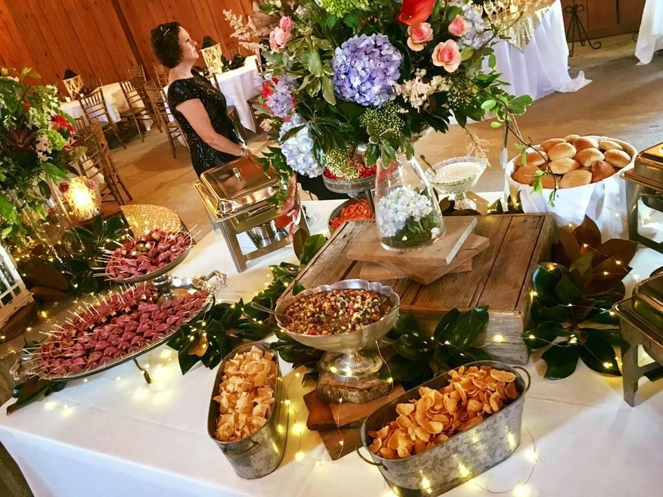 Elegant buffet table with flowers, fruit, and appetizers at a decorated indoor event