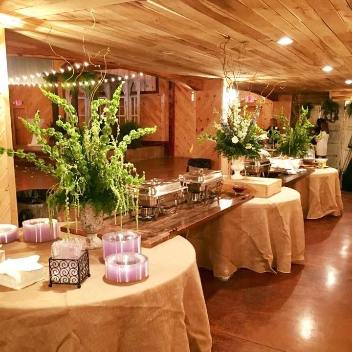 Buffet tables with tan linens and floral centerpieces in a warmly lit event hall