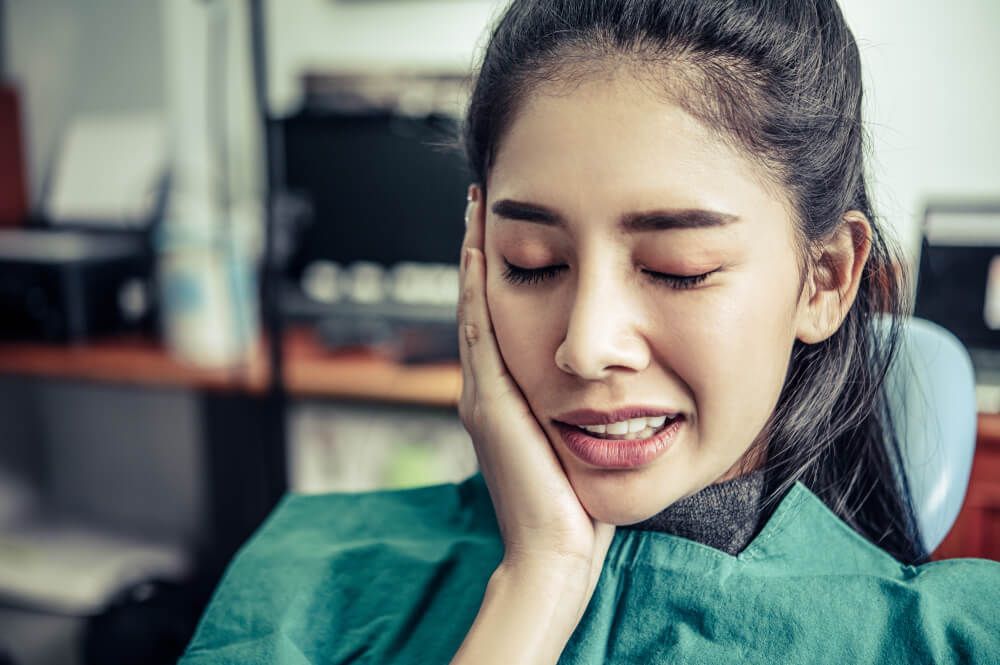 Woman holding her cheek from wisdom teeth pain