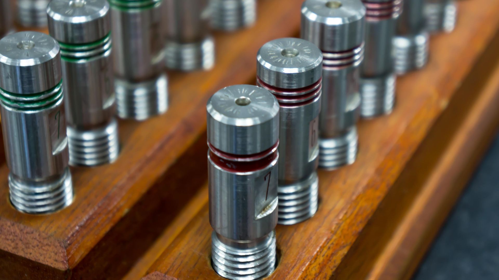 A bunch of metal cylinders are sitting on top of a wooden shelf.