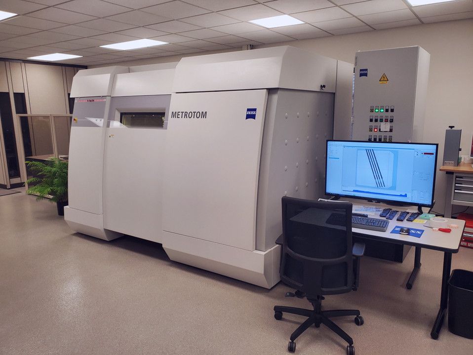 A computer monitor is sitting on a desk in front of a large machine.