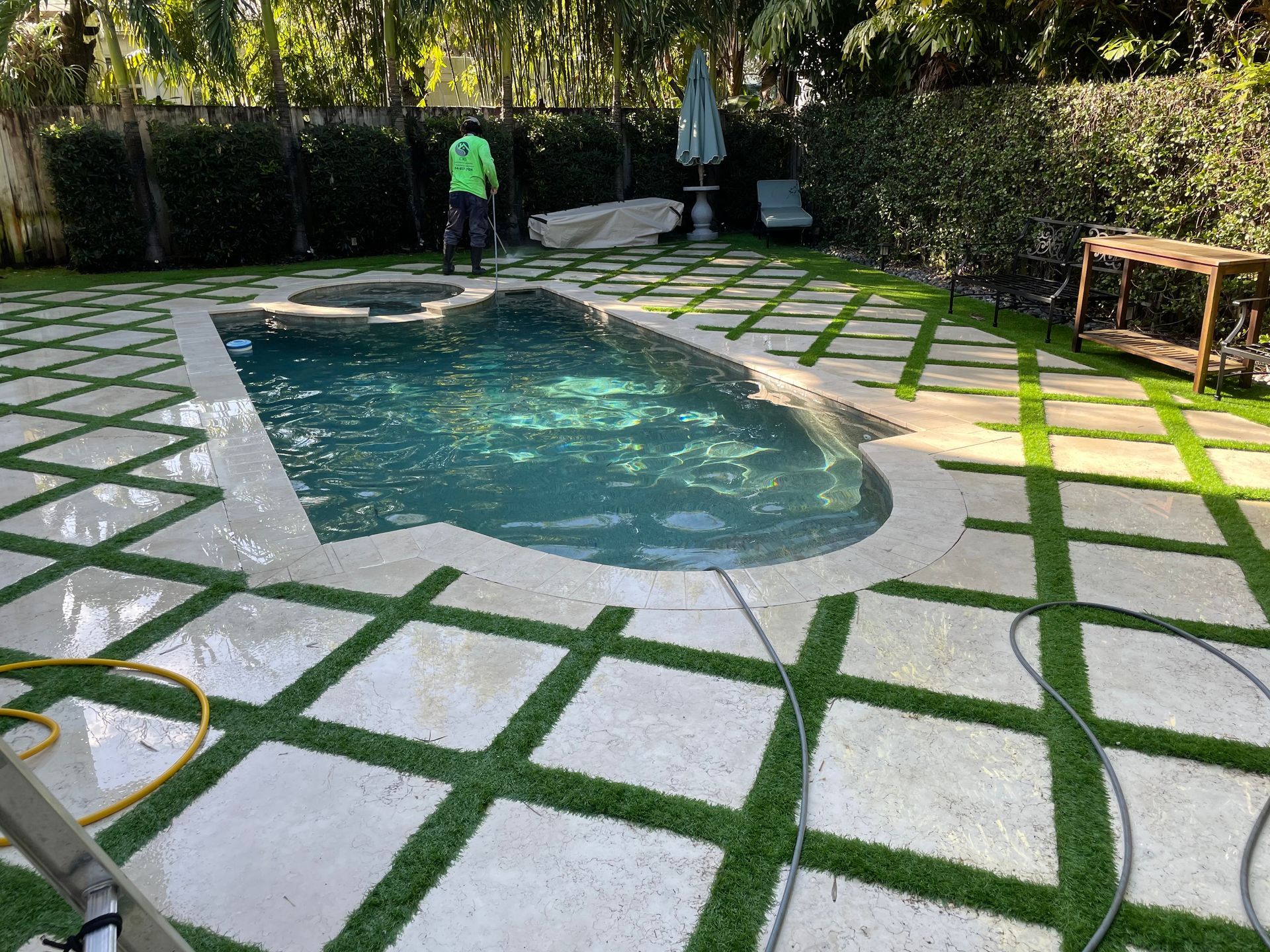 A man is kneeling down in a garden holding rolls of turf.