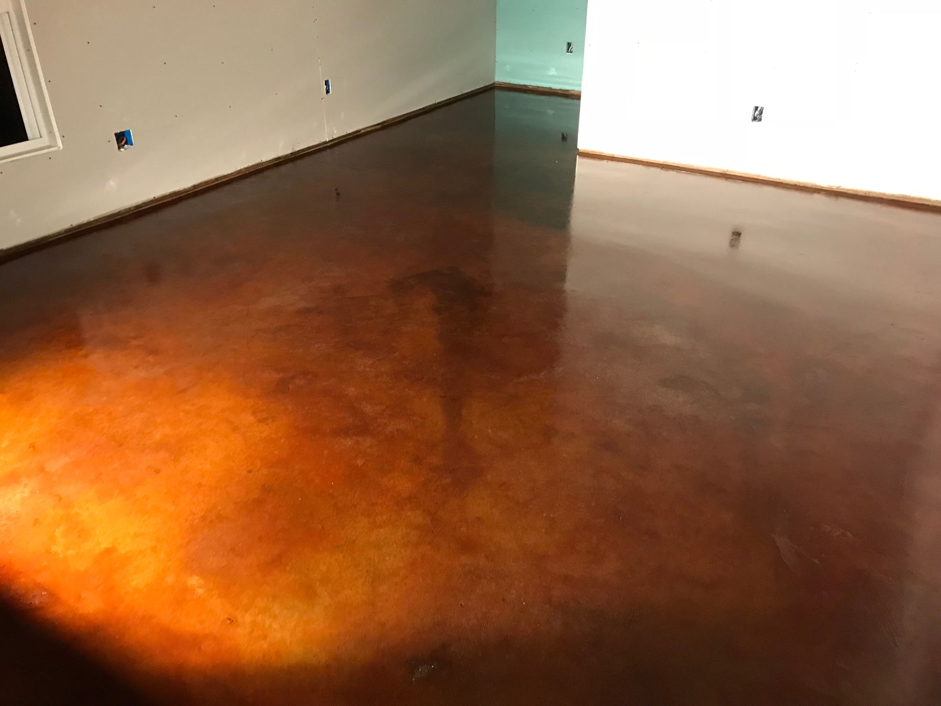 Image of a brown acid-stained interior concrete floor, showcasing rich, earthy tones and a mottled texture.