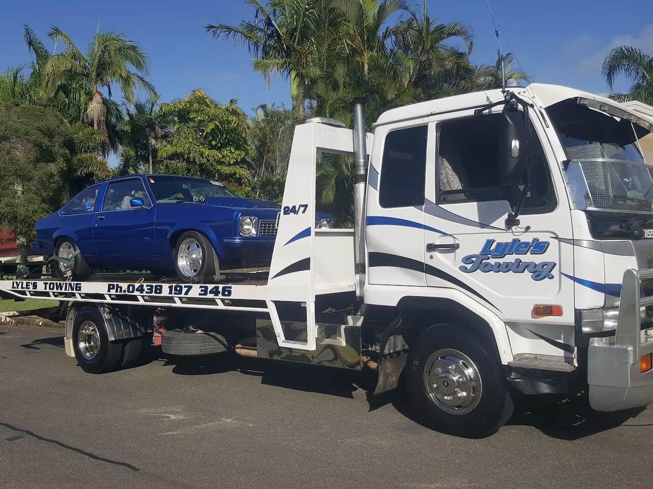 A White Tow Truck With Blue Car On It — Lyle's Towing In Little Mountain, QLD