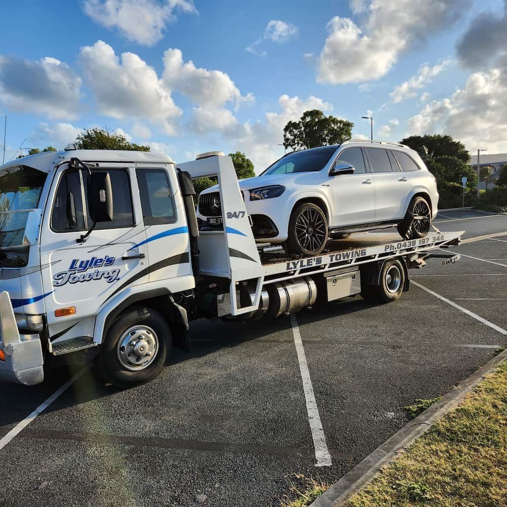 A White SUV is Being Towed by a Tow Truck — Lyle's Towing In Little Mountain, QLD