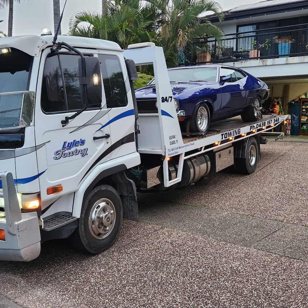 A Tow Truck With a Blue Car on the Back is Parked — Lyle's Towing In Little Mountain, QLD