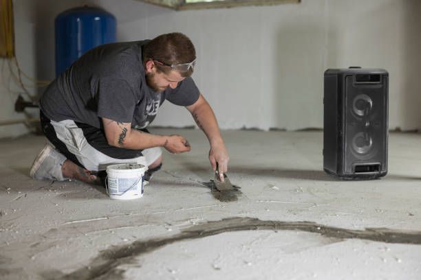 Accurate Foundation Repair worker sealing cracks in a concrete floor during structural foundation re