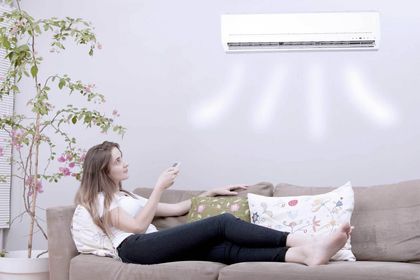 Woman Using Remote Control of Air Conditioner — Ashland, KY — ArTron Heating & Air Conditioning