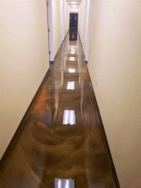 Long hallway with metallic gold epoxy flooring, tan walls, and a door at the end.