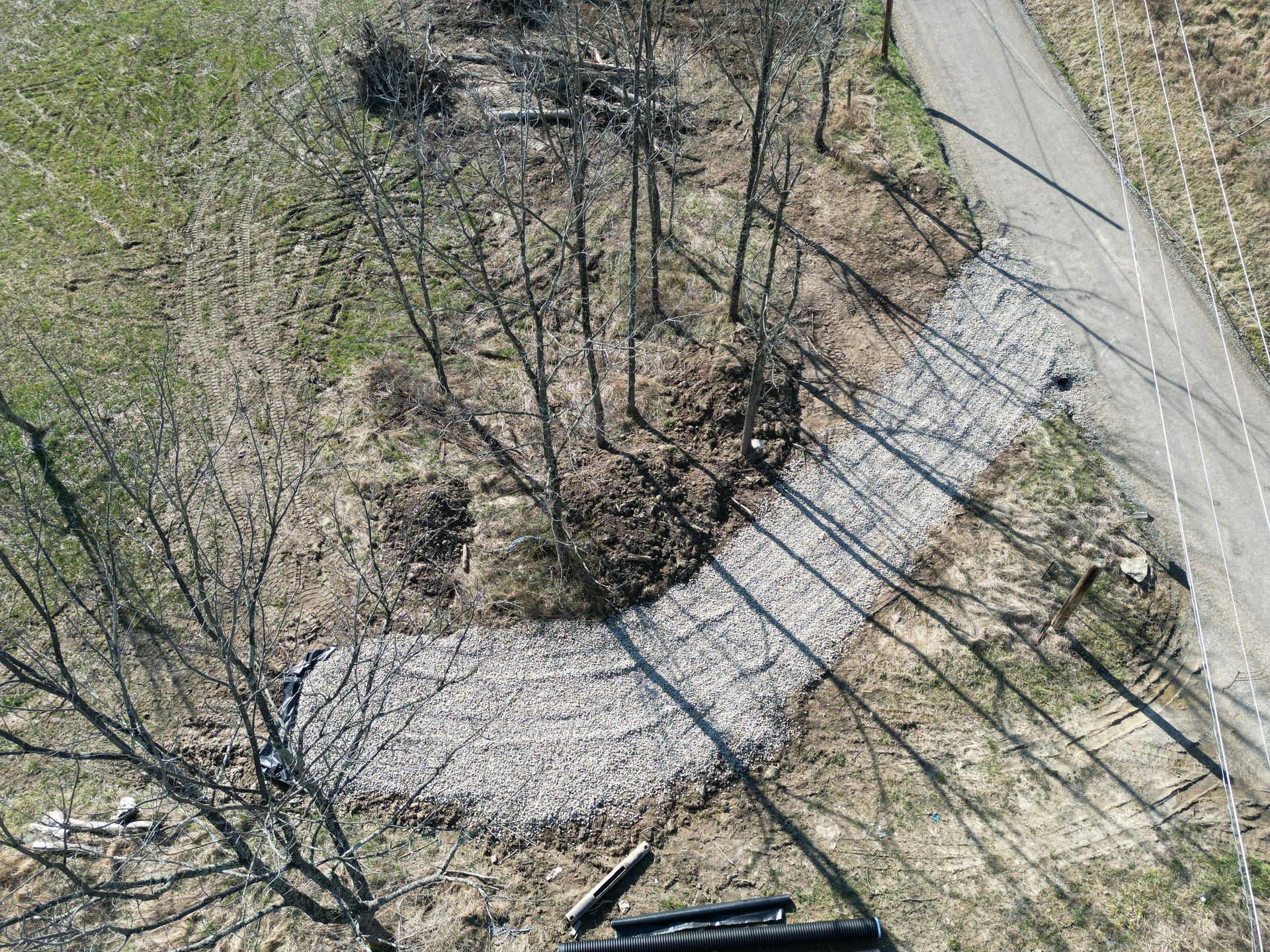 An aerial view of a dirt road surrounded by trees and grass.