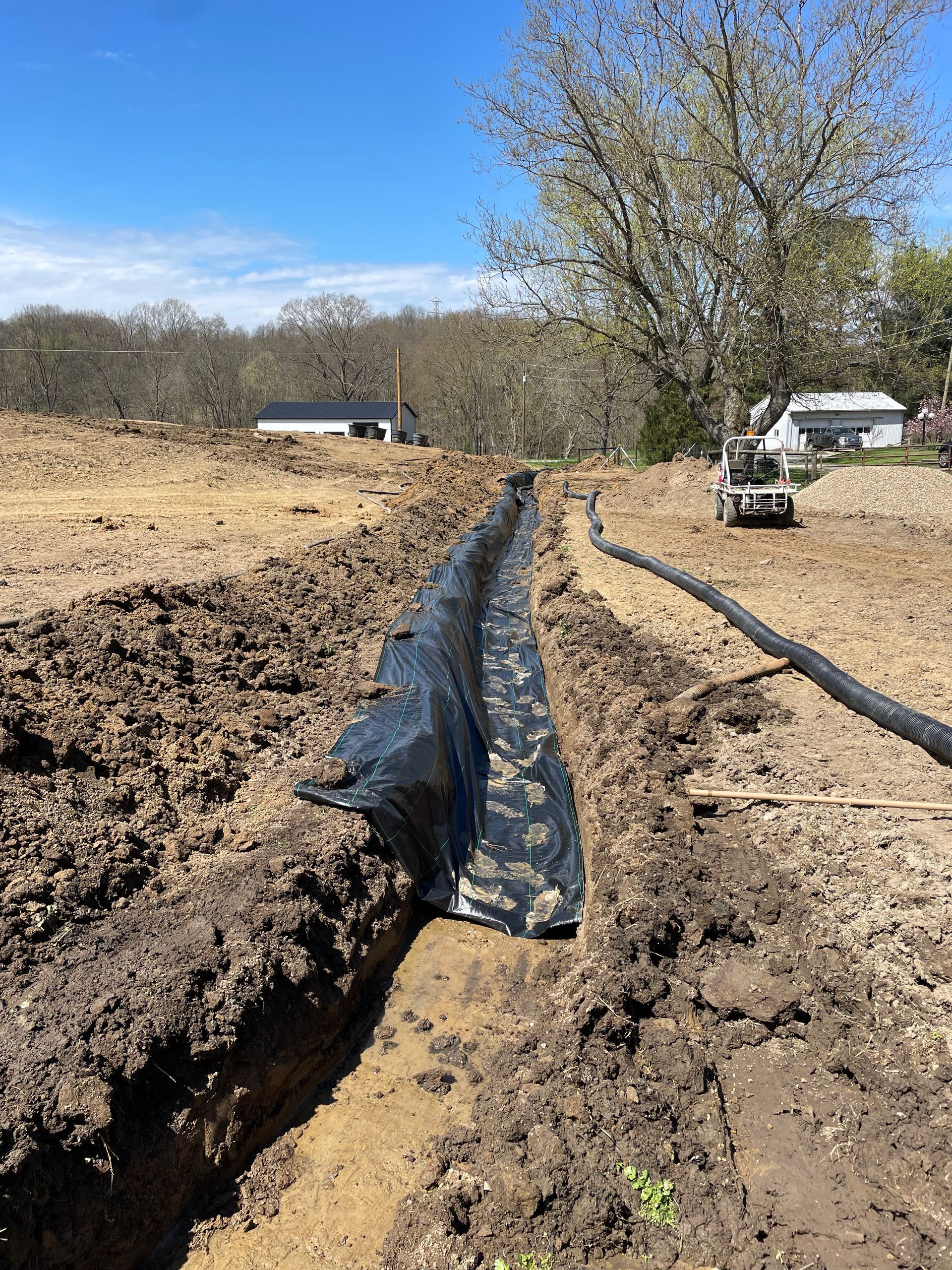 A drainage pipe is being installed in a muddy field.