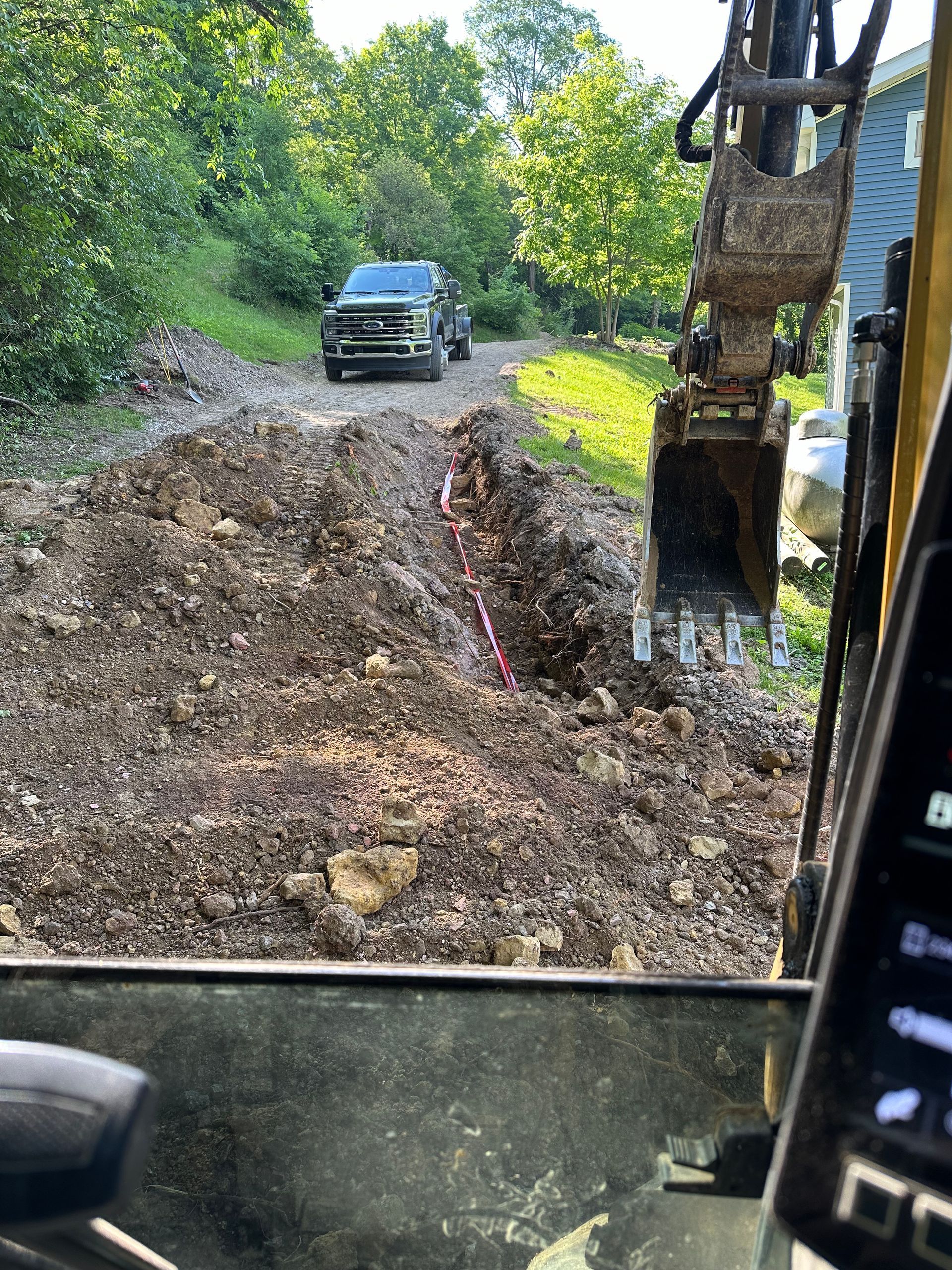 A truck is driving down a dirt road next to a bulldozer.