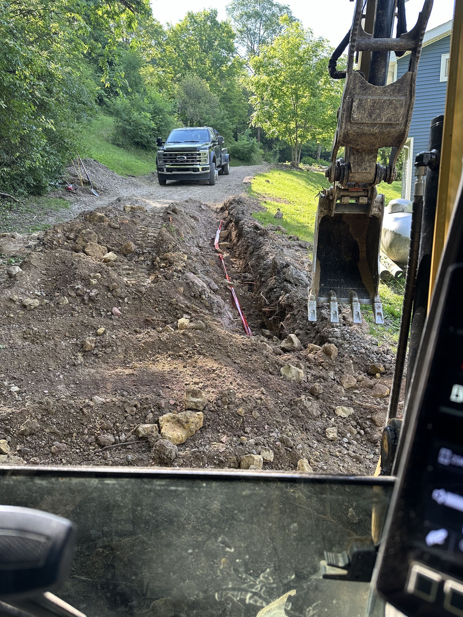 A truck is driving down a dirt road next to a large pile of dirt.