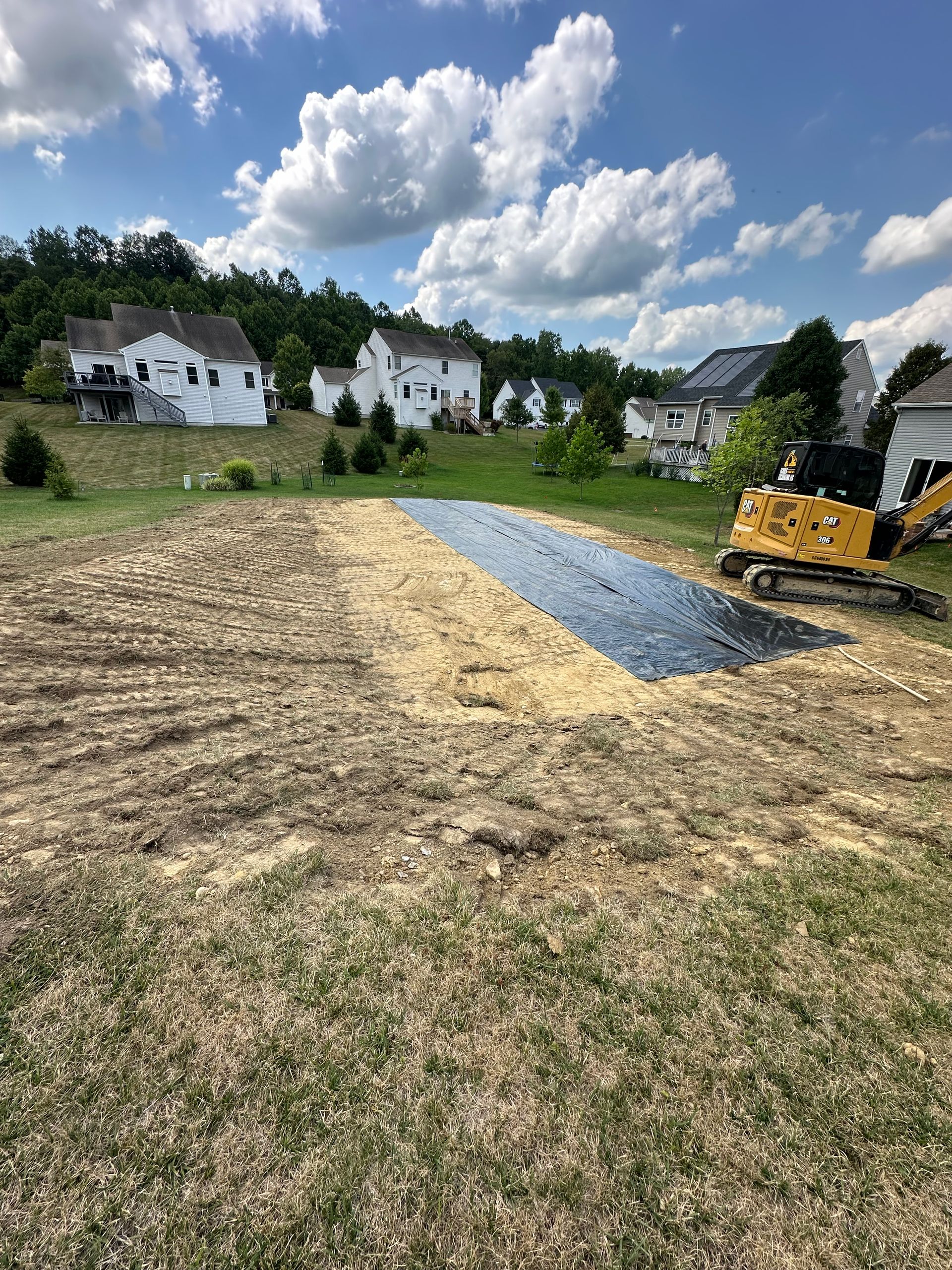 A yellow excavator is sitting on top of a dirt field.