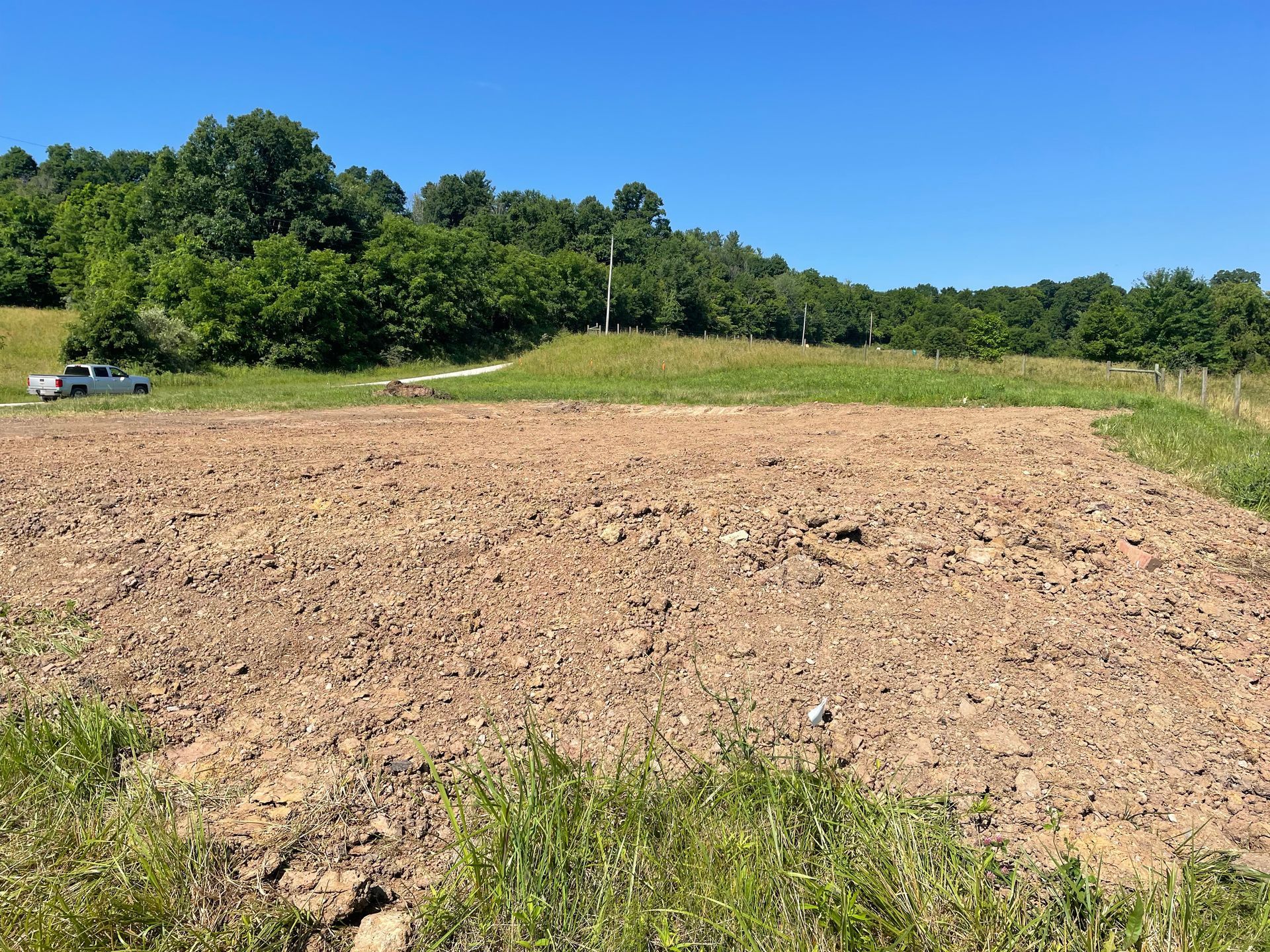A dirt field with trees in the background on a sunny day.