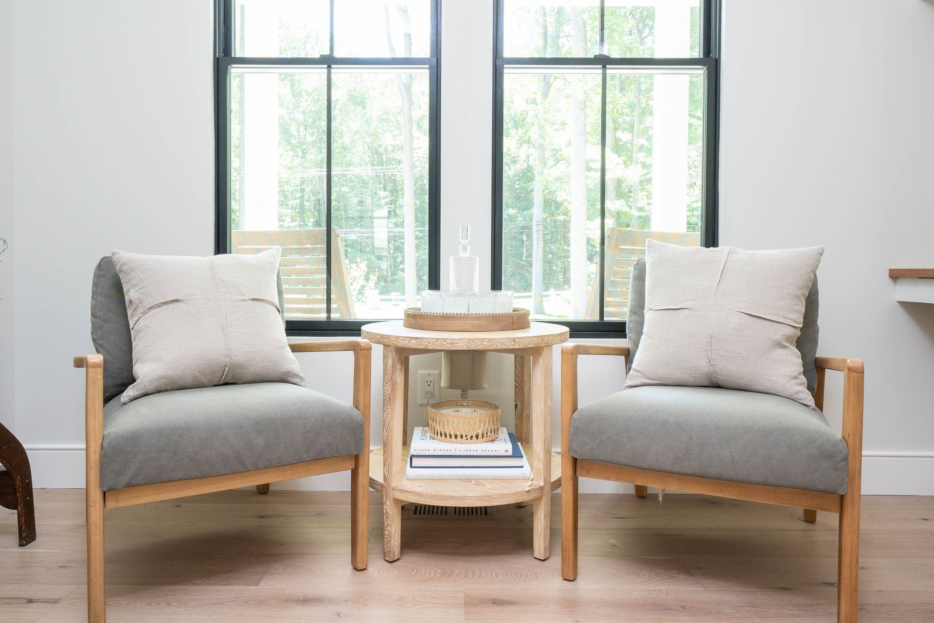 A living room with two chairs and a table in front of a window.