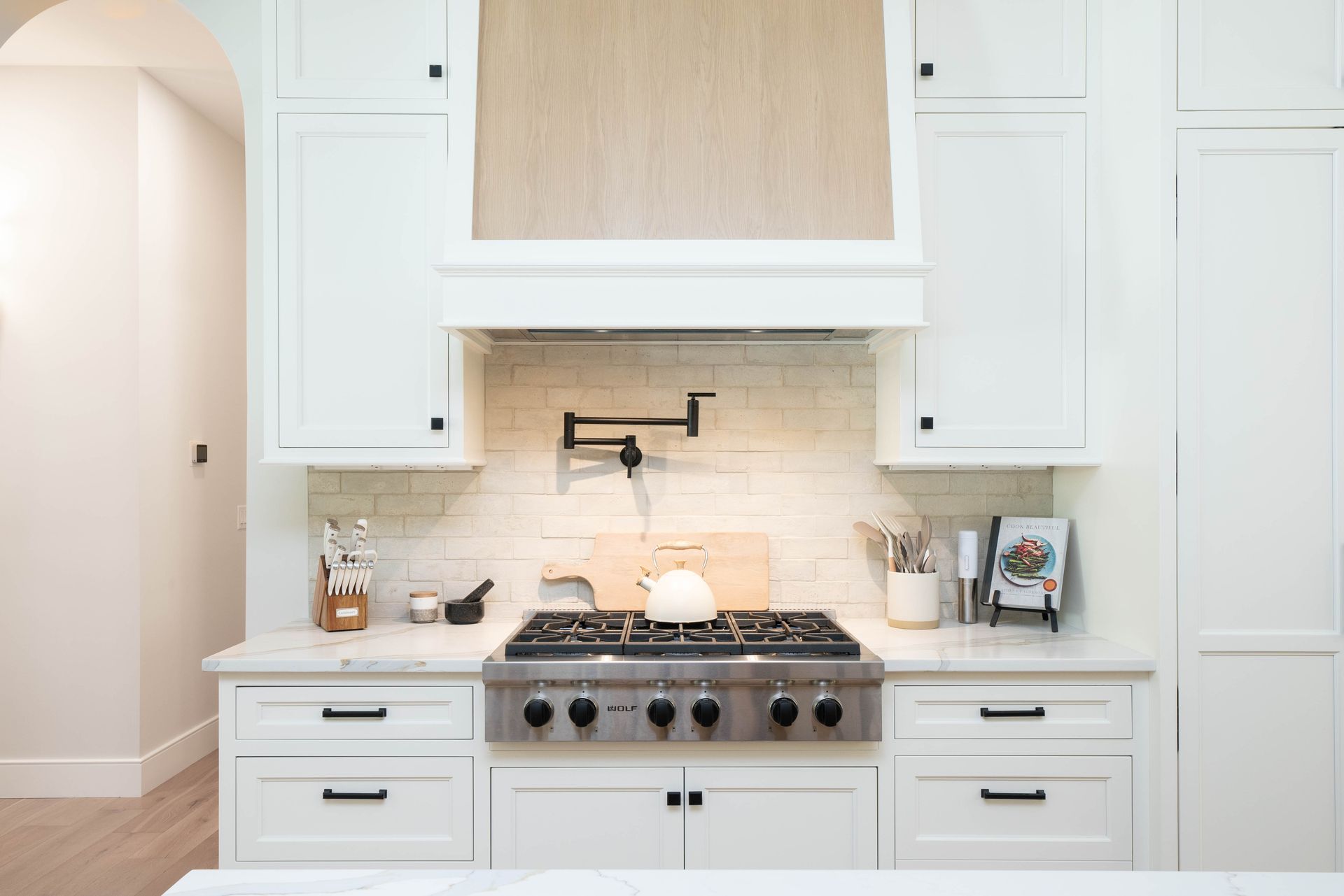A kitchen with white cabinets and a stove top oven.