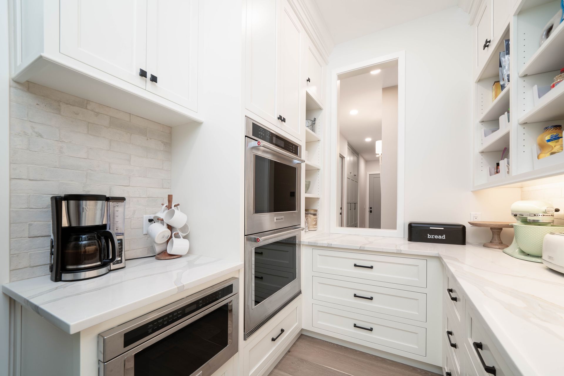 A kitchen with white cabinets , stainless steel appliances , and a coffee maker.
