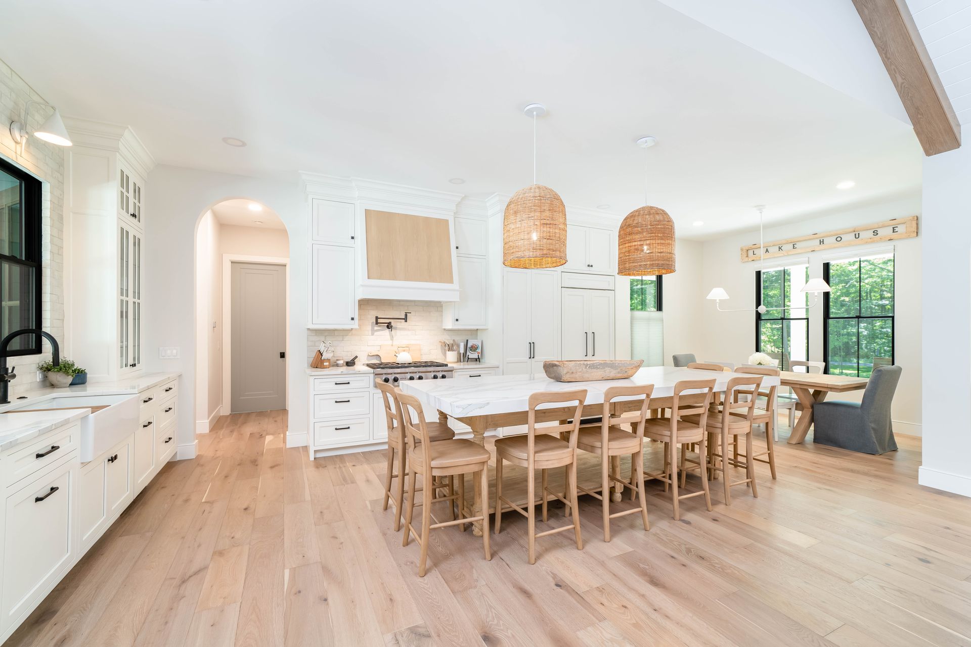 A kitchen with white cabinets , wooden floors , a table and chairs.