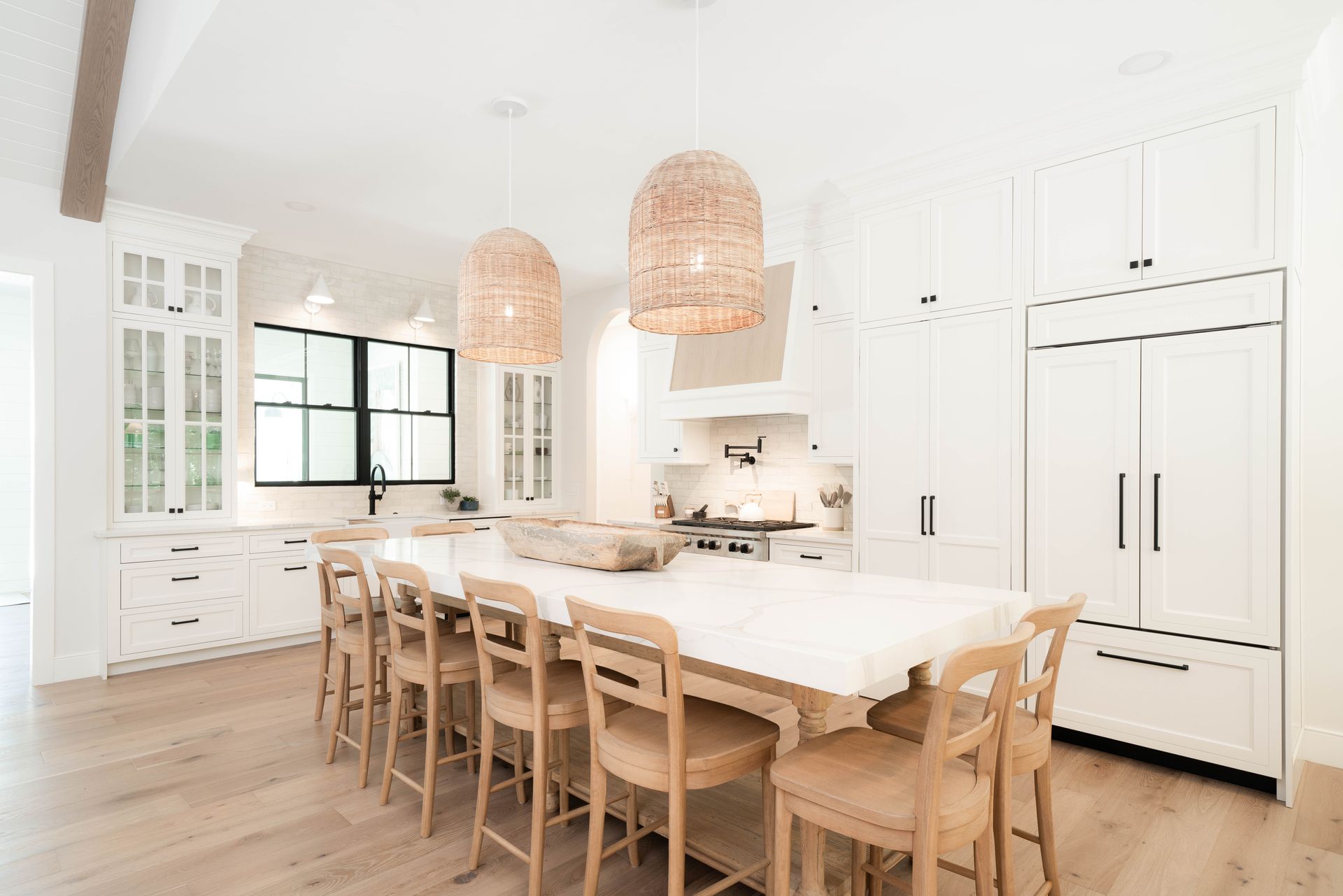 A kitchen with a long table and chairs in it.