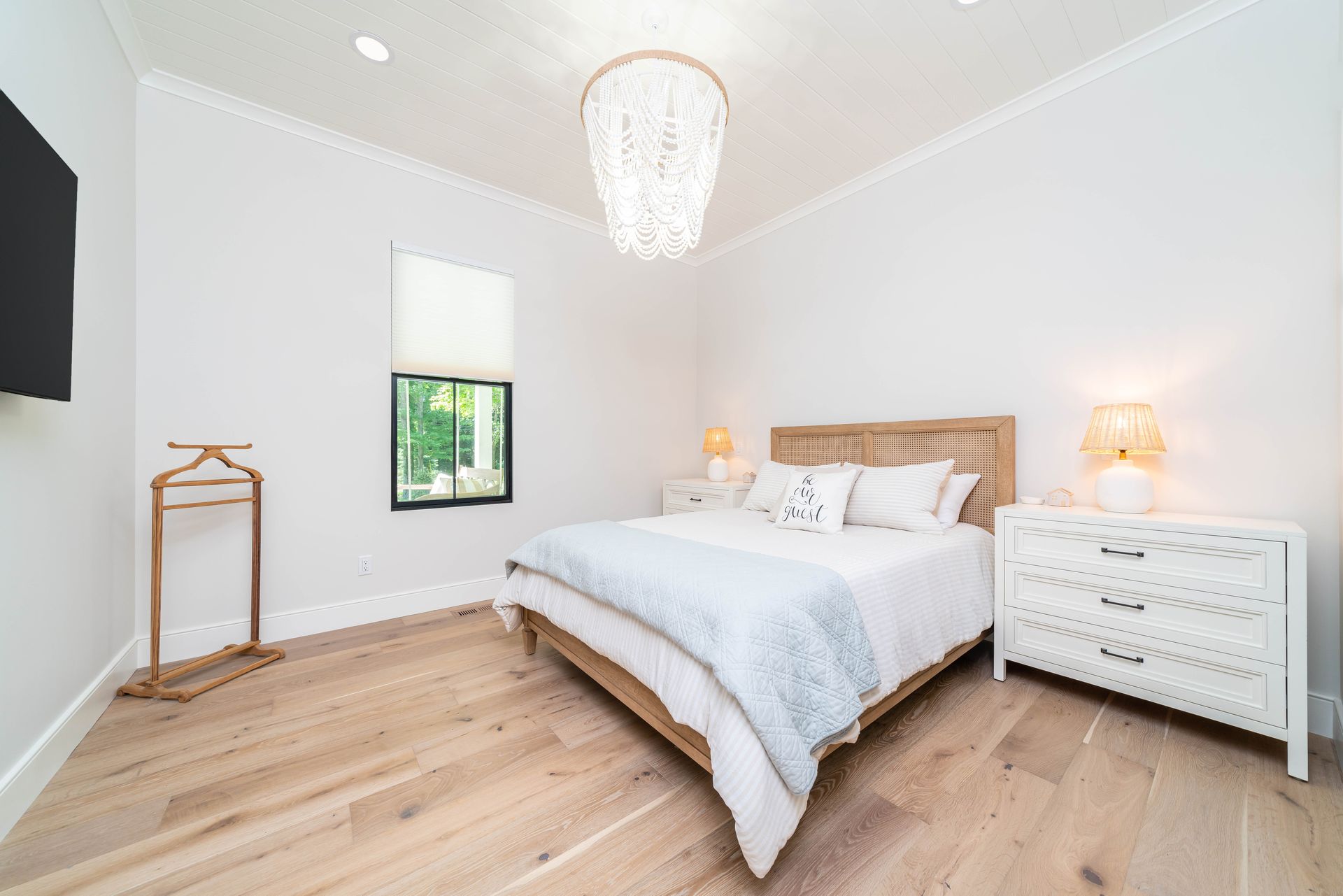 A bedroom with a king size bed , dresser , nightstand , and television.