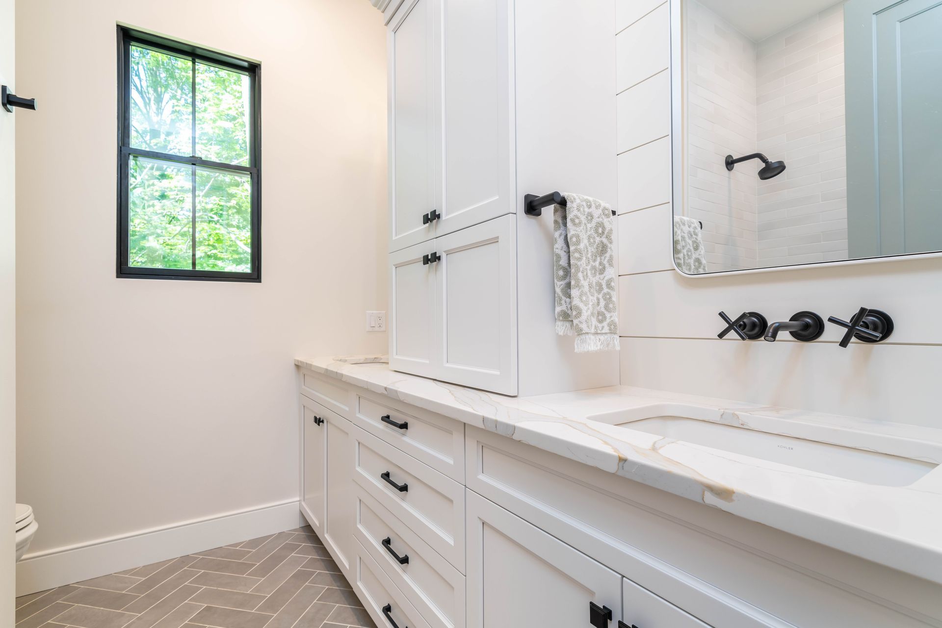 A bathroom with two sinks , a mirror and a window.