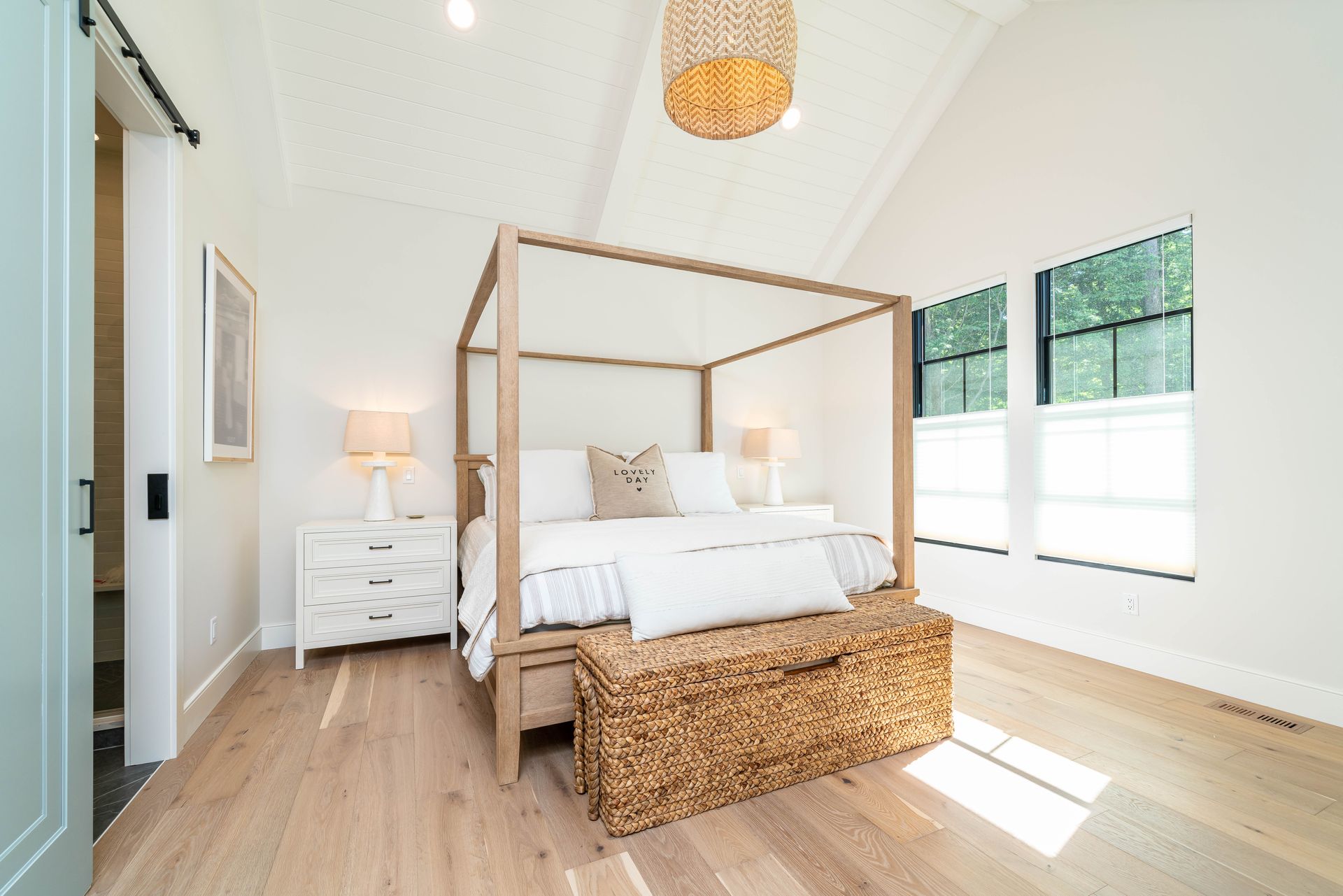 A bedroom with a canopy bed and a wicker bench.
