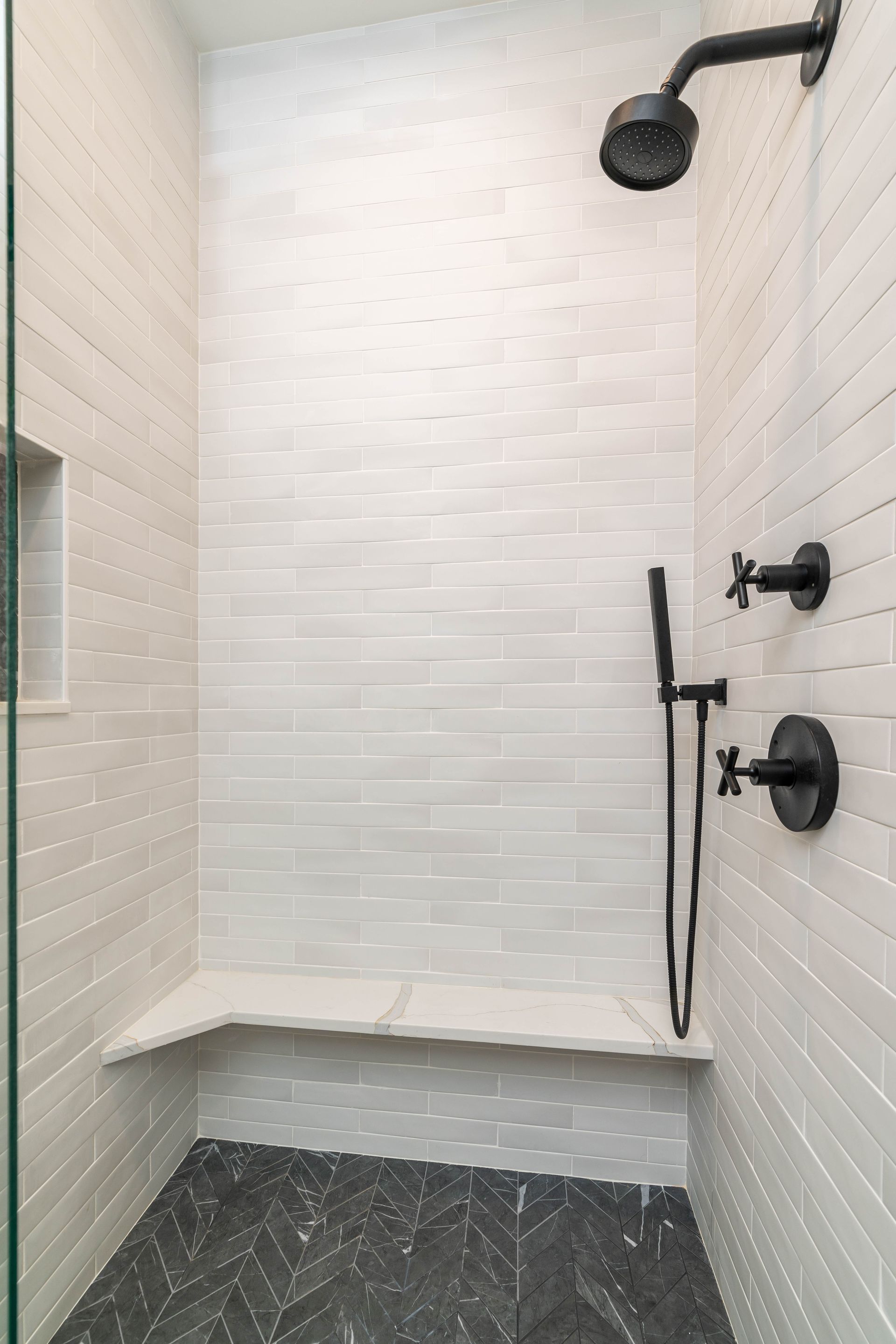 There is a shower with a bench and a shower head.