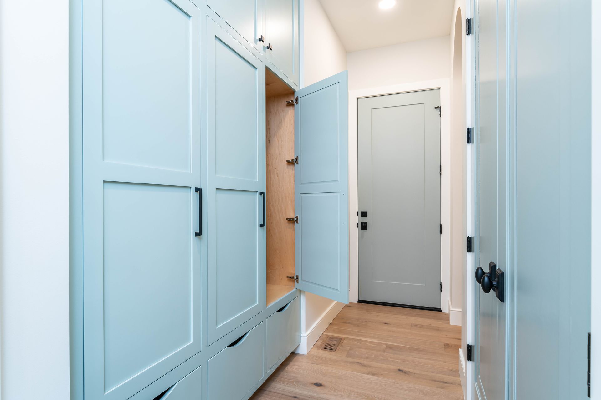 A hallway with blue cabinets and drawers and a door.