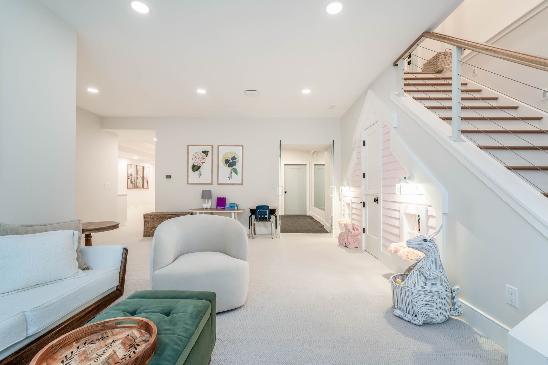 A living room with a couch , chair , ottoman and stairs.