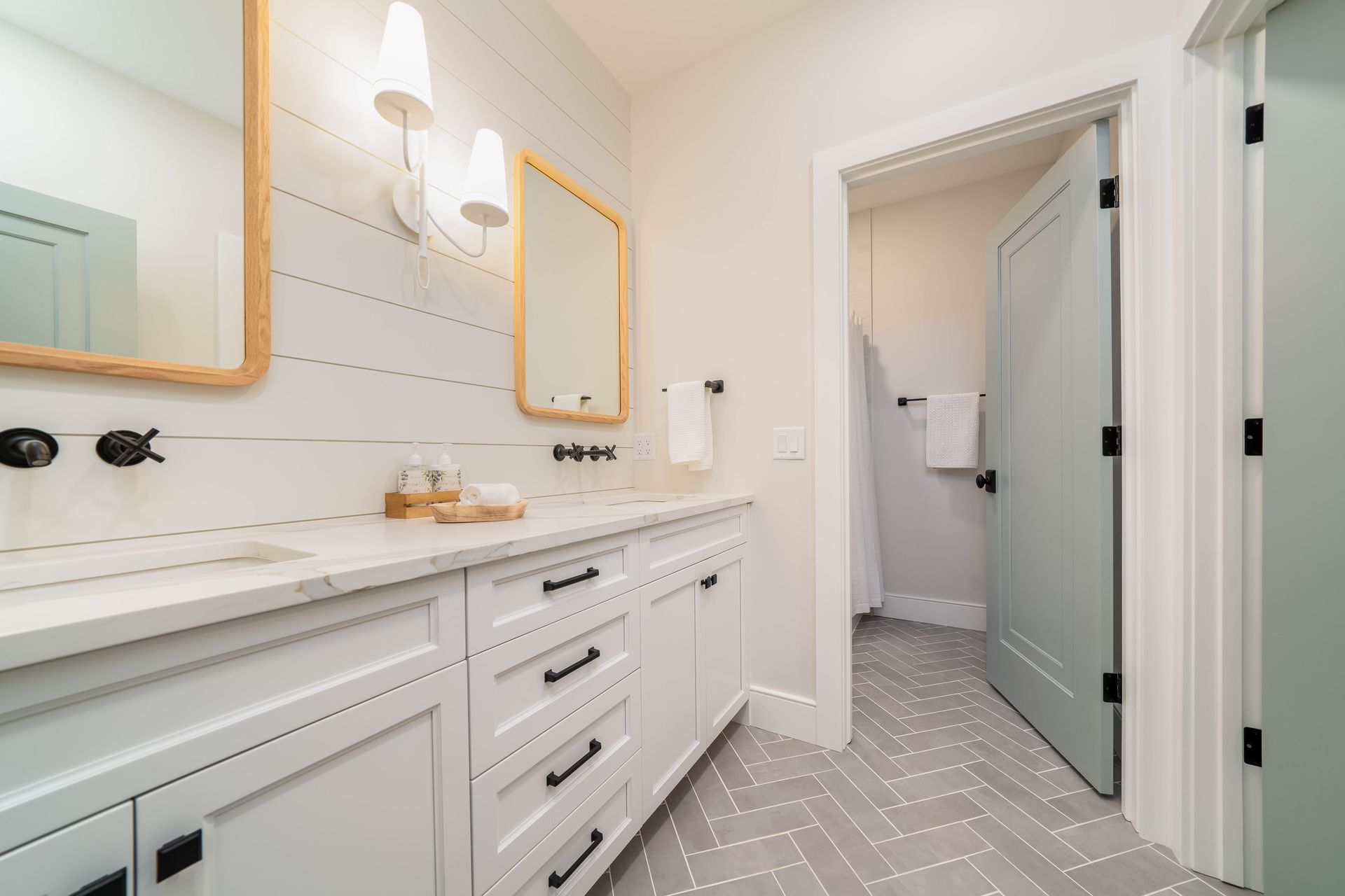 A bathroom with two sinks , two mirrors , and a walk in shower.