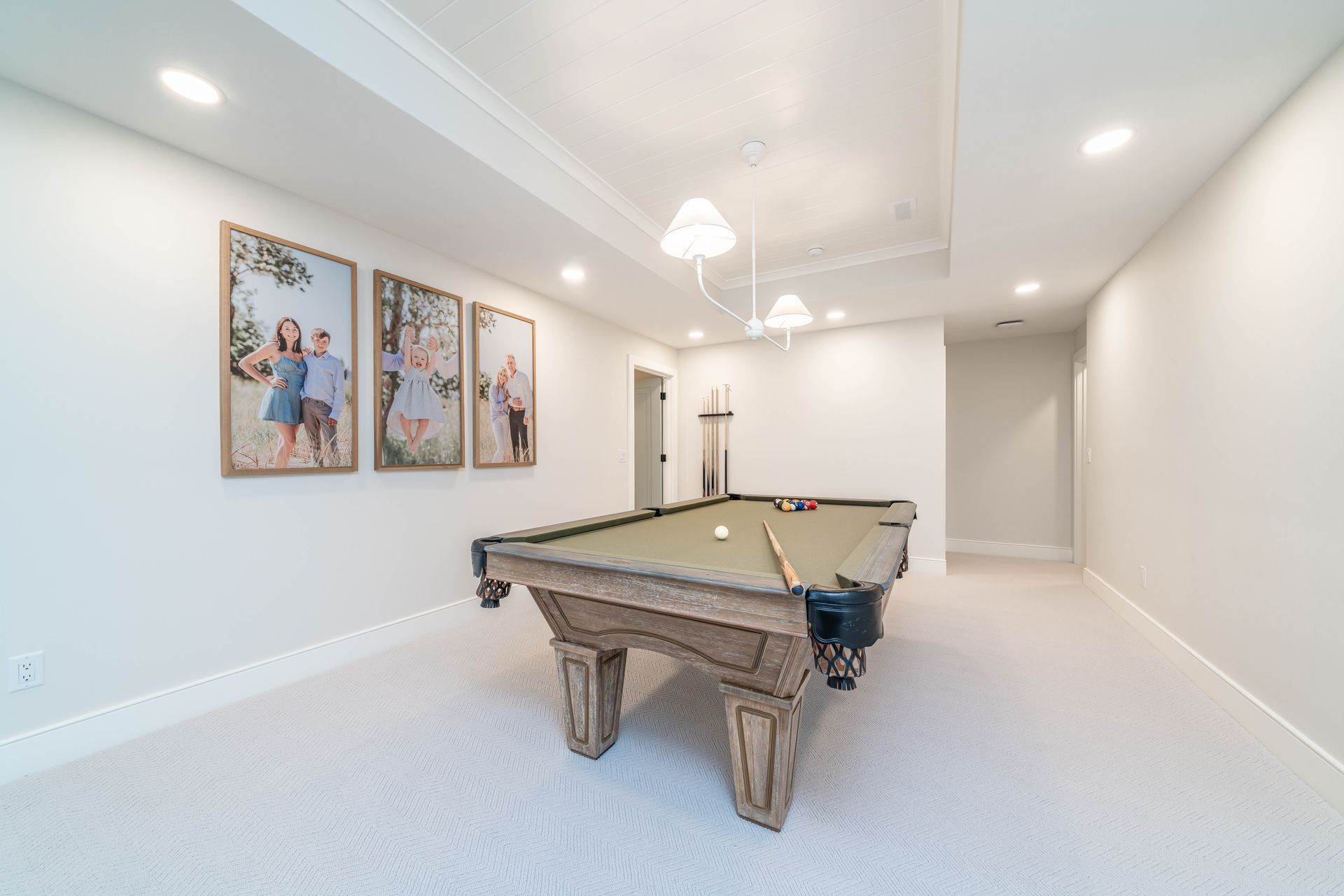A pool table in a basement with pictures on the wall.