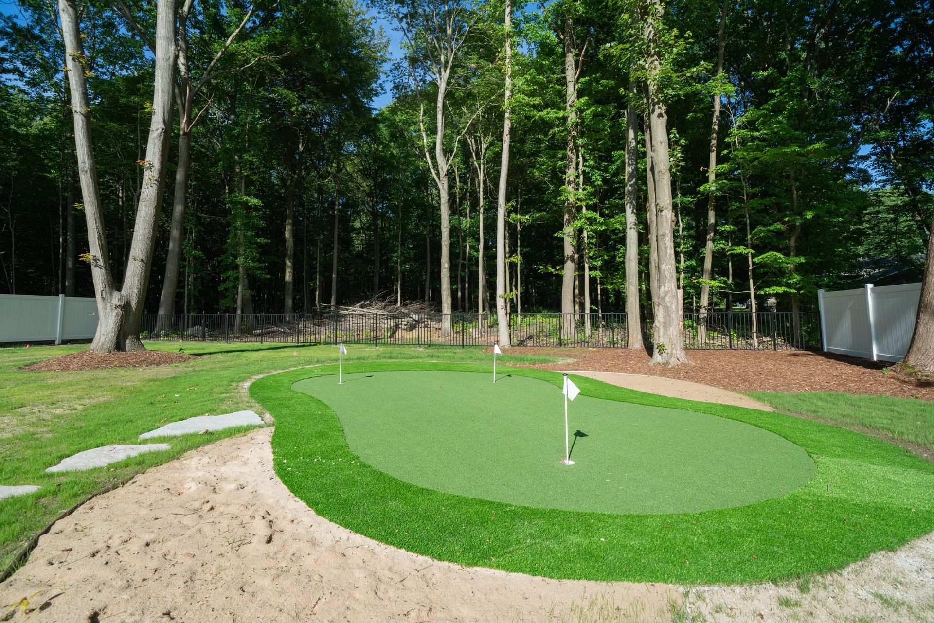 A green putting green in the middle of a forest.