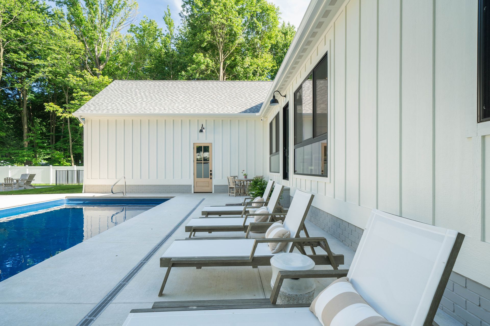 A row of lounge chairs are lined up next to a swimming pool.