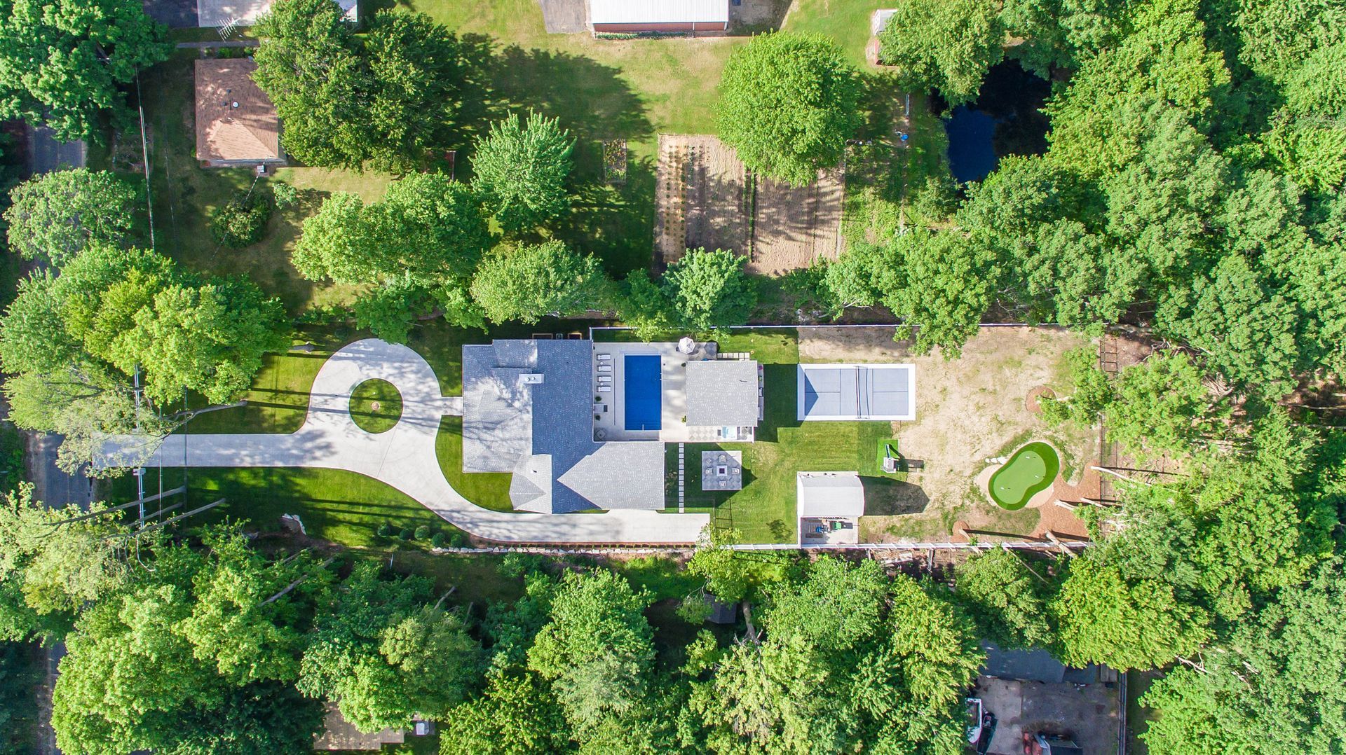 An aerial view of a house surrounded by trees and grass.