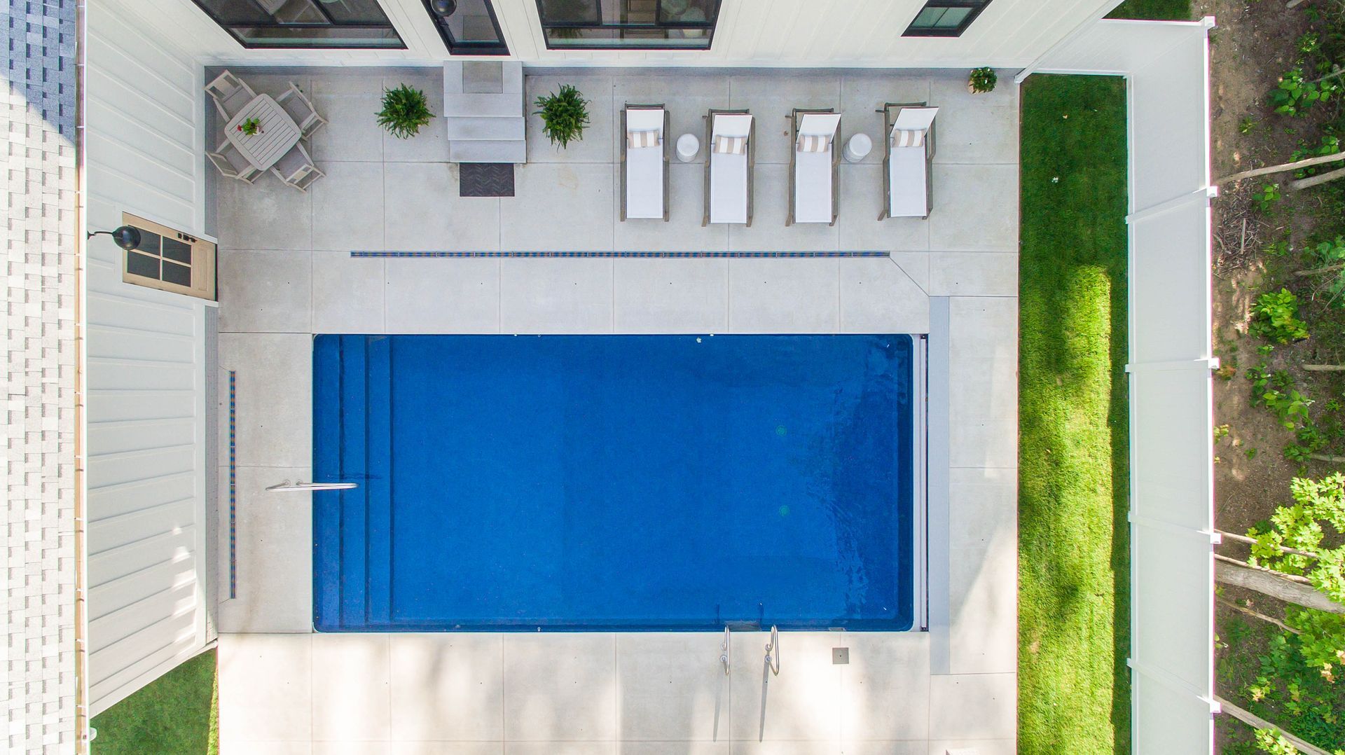 An aerial view of a large swimming pool in the backyard of a house.