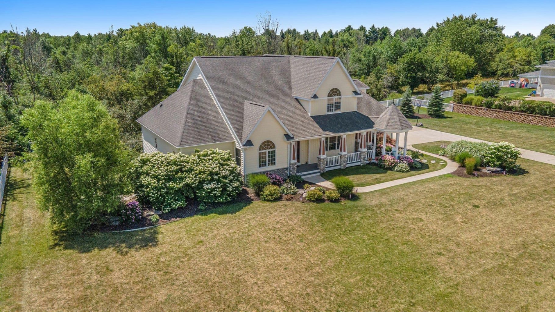 An aerial view of a large white house surrounded by trees and grass.