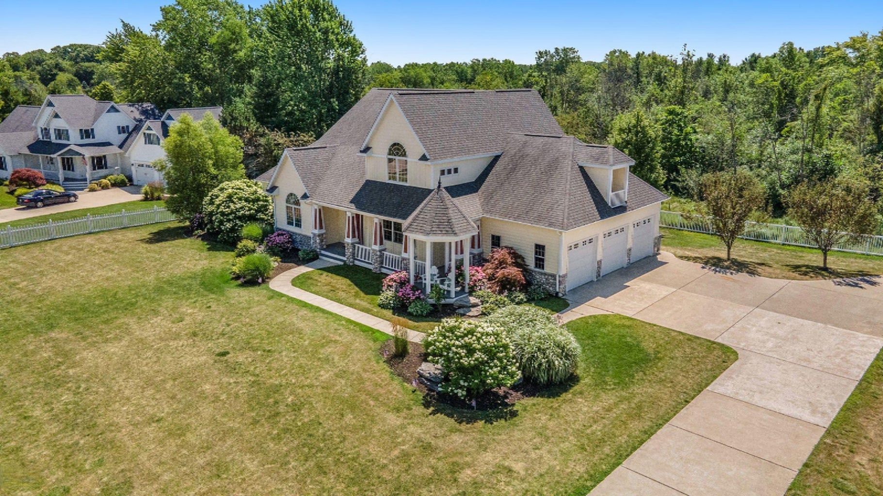 An aerial view of a large house with a driveway leading to it surrounded by trees.