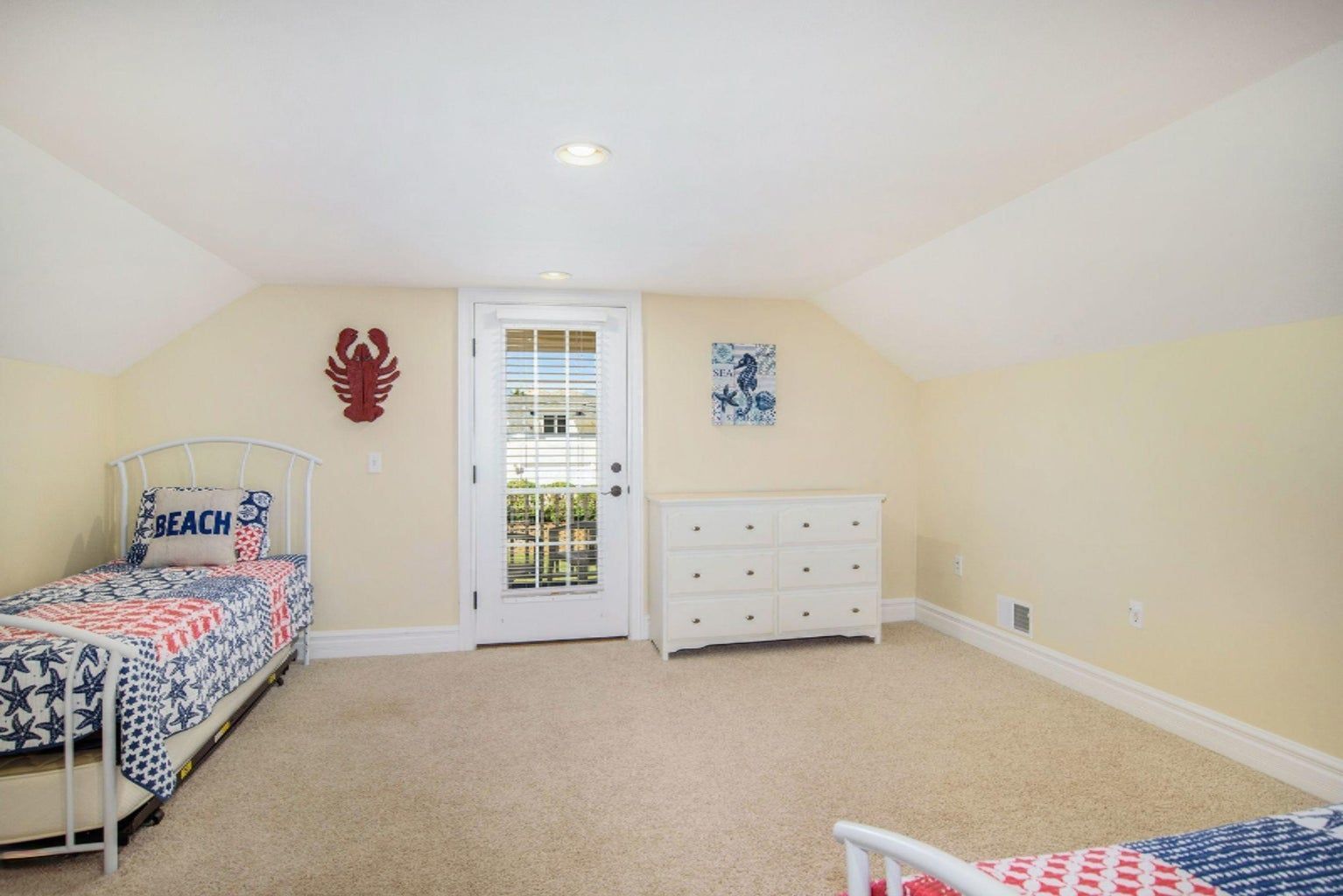 A bedroom with two beds , a dresser and a door.