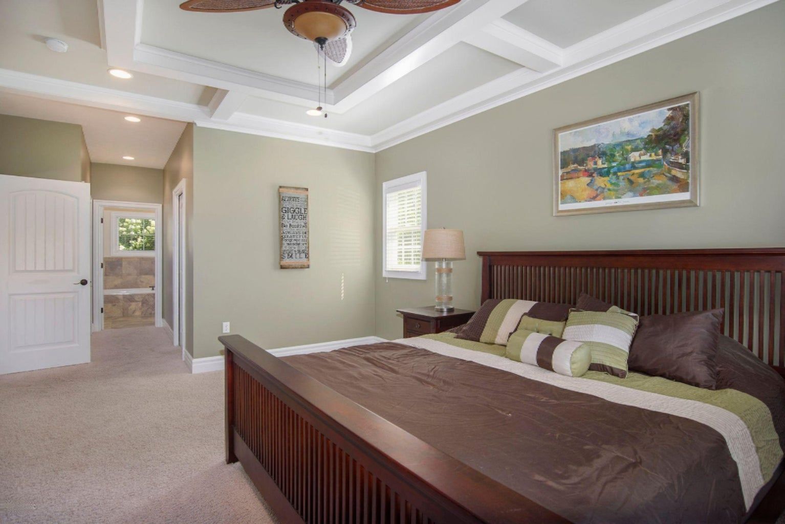 A bedroom with a large bed and a ceiling fan.
