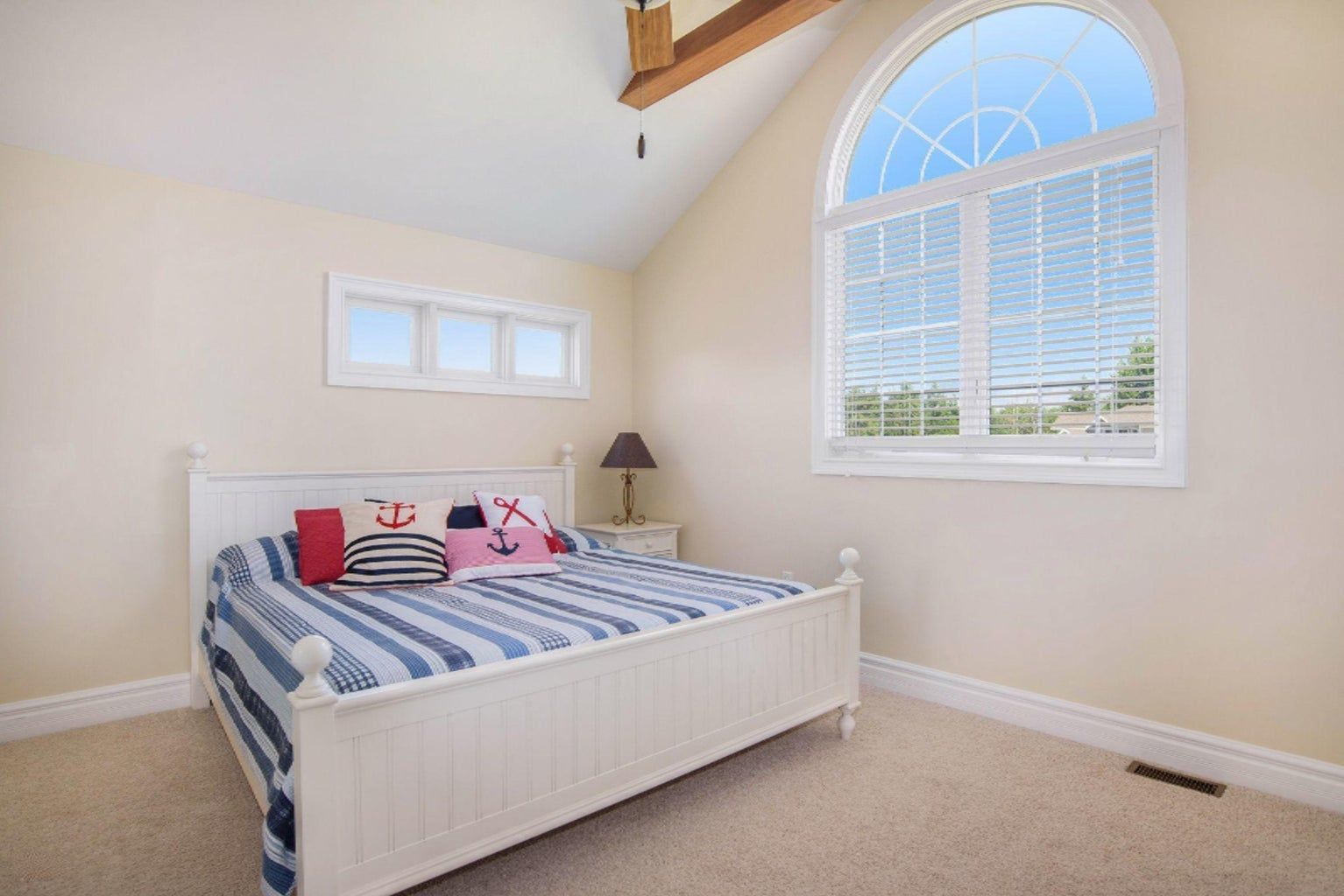 A bedroom with a bed and a window with blinds.