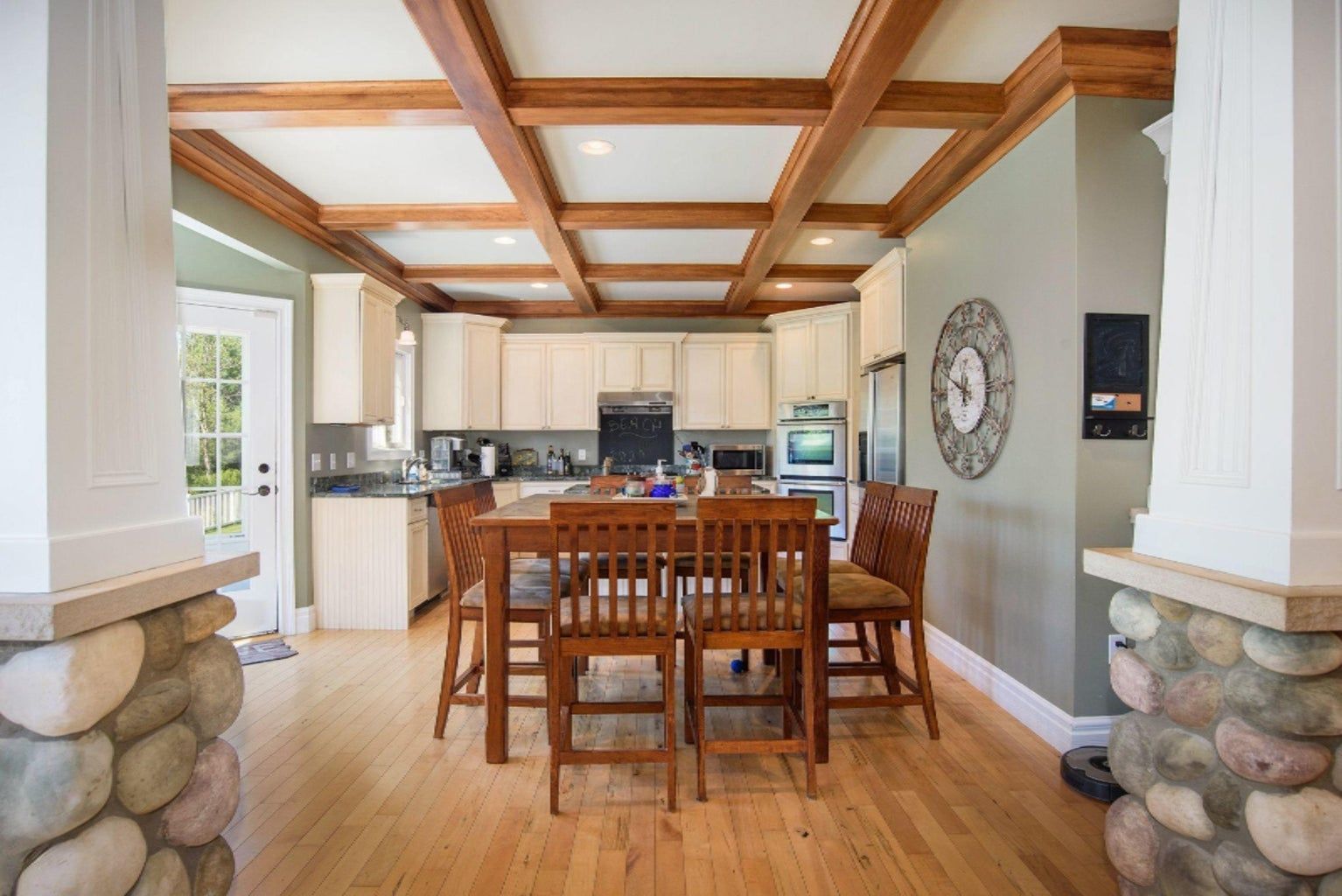 A kitchen with a wooden table and chairs and a coffered ceiling.