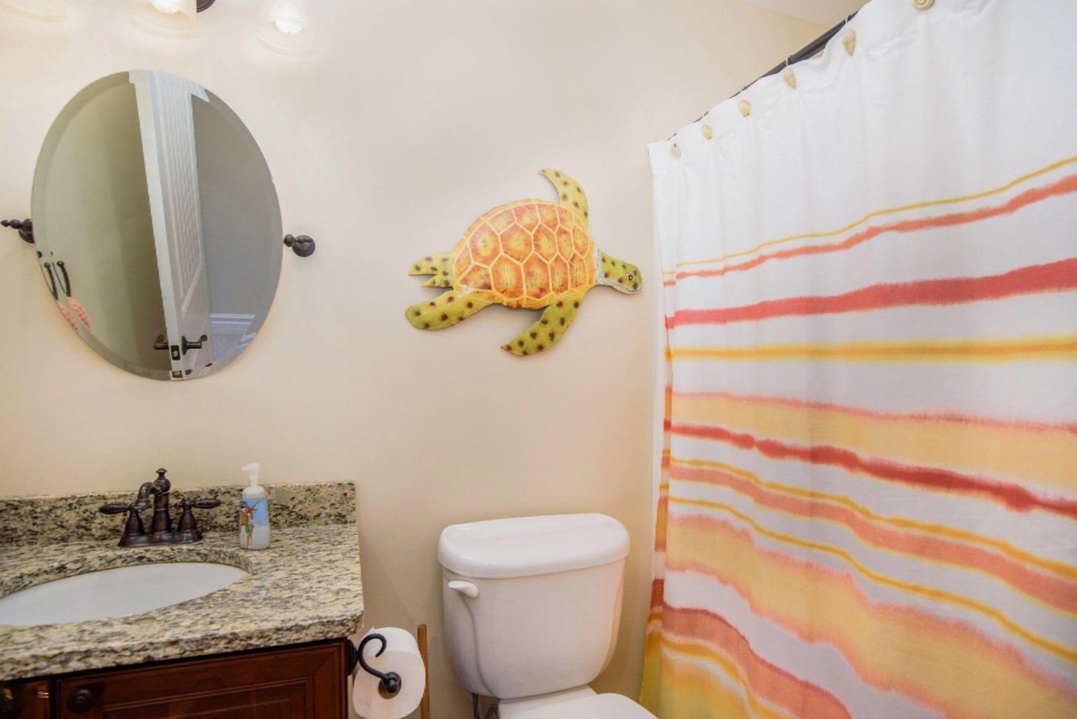A bathroom with a toilet , sink , mirror and shower curtain.