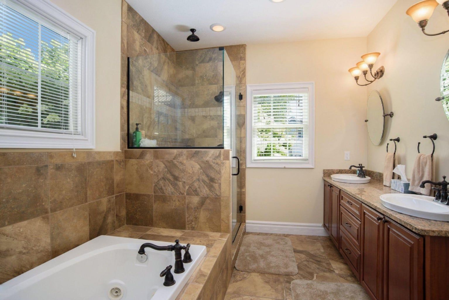 A bathroom with a tub , sinks , and a walk in shower.