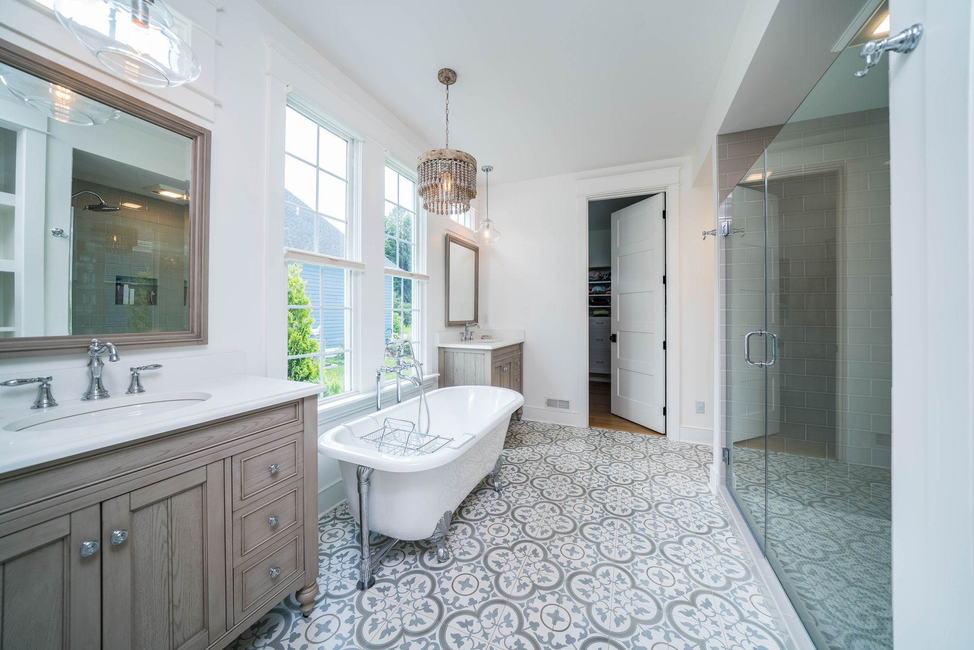 Elegant white bathroom with patterned floor, clawfoot tub, glass shower, and vanity.