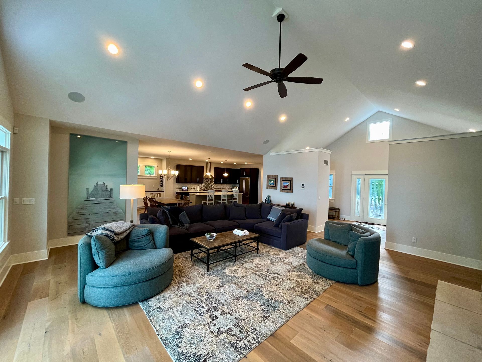 Spacious living room with a vaulted ceiling, sectional sofa, and two teal swivel chairs.